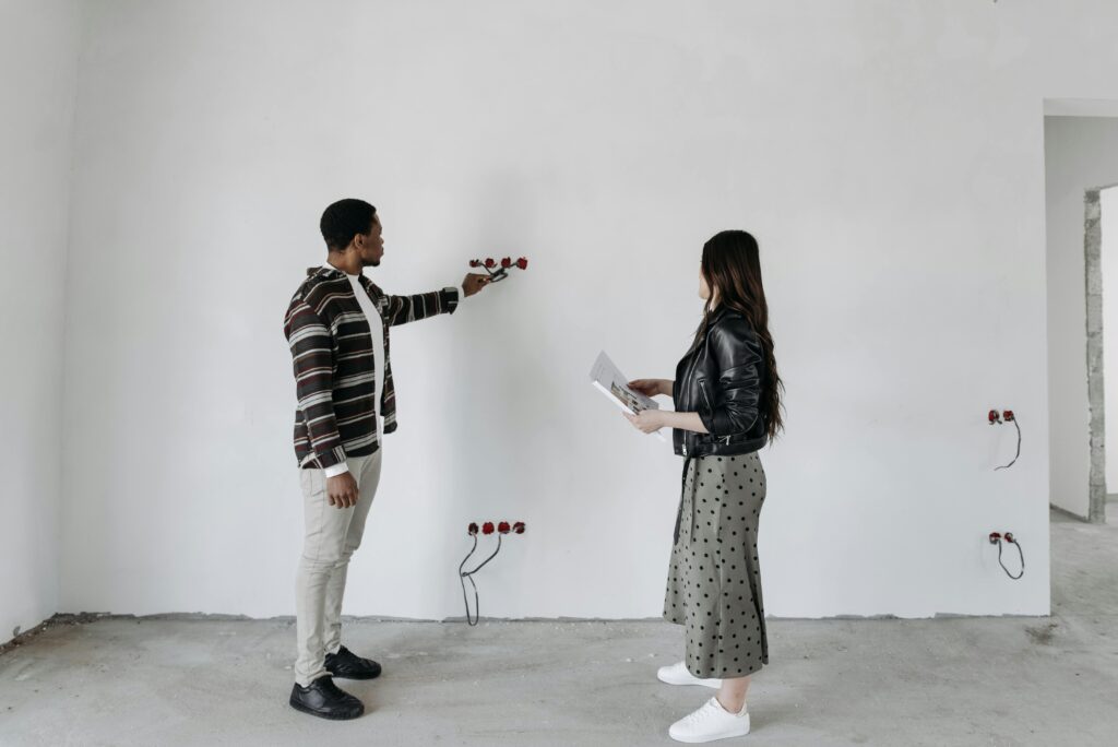A man and woman examining wiring installations in an unfinished home's interior.